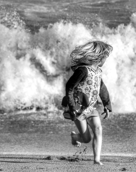 girl at beach running from waves