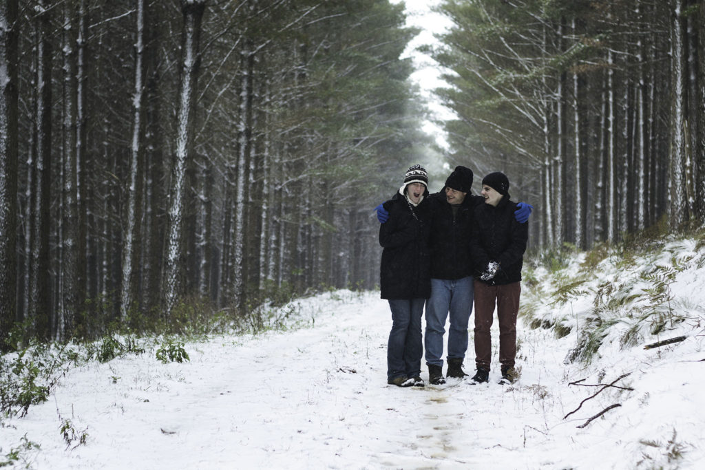 three people standing together in snowy forest
