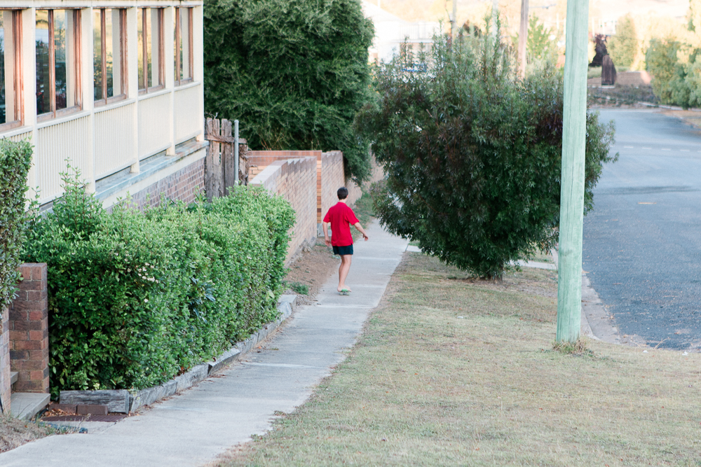 boy riding skateboard down footpath