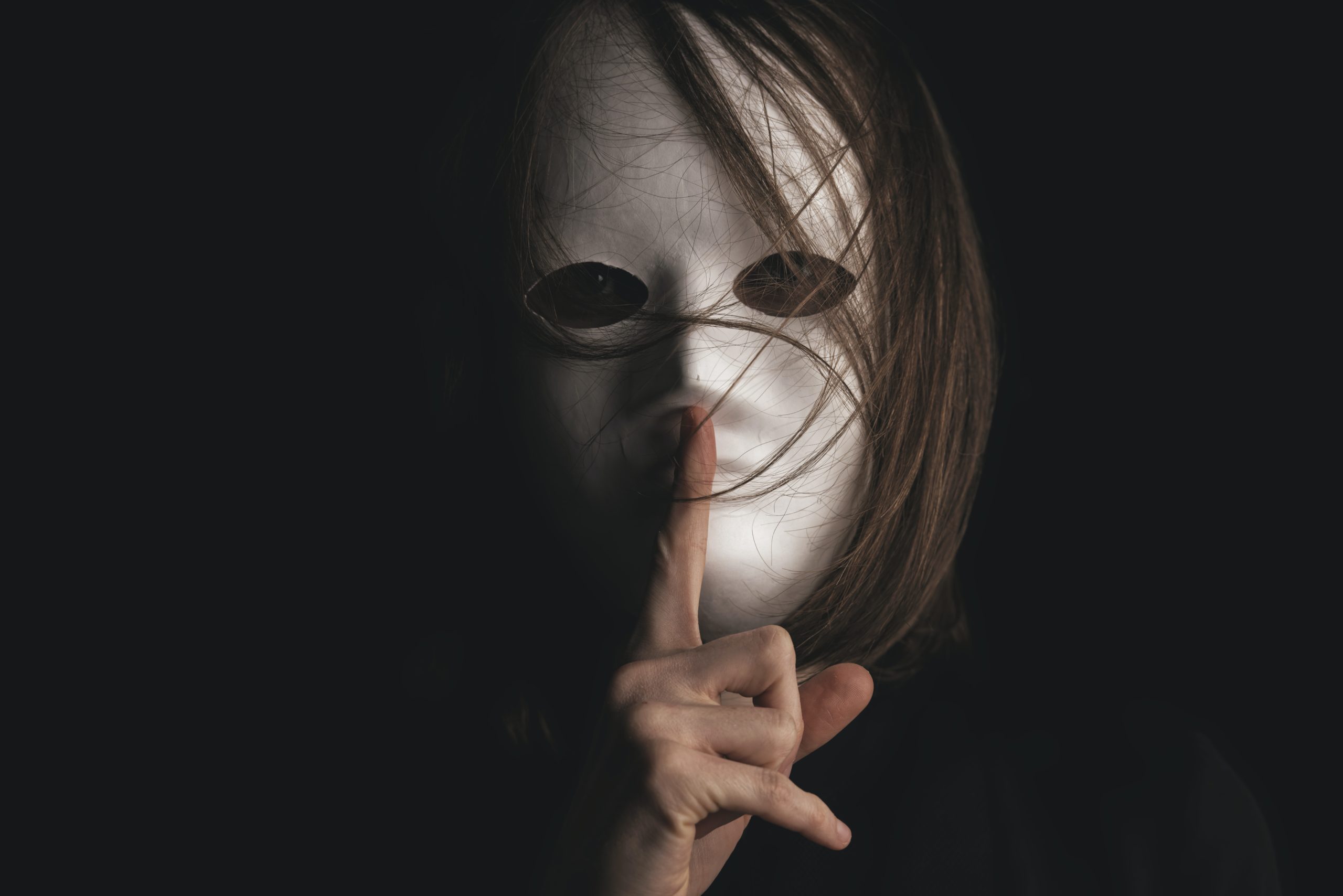 woman wearing white mask with finger to lips