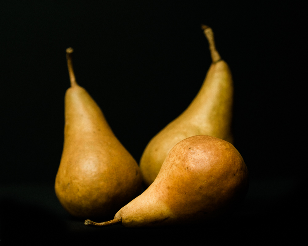 three brown pears on a black background
